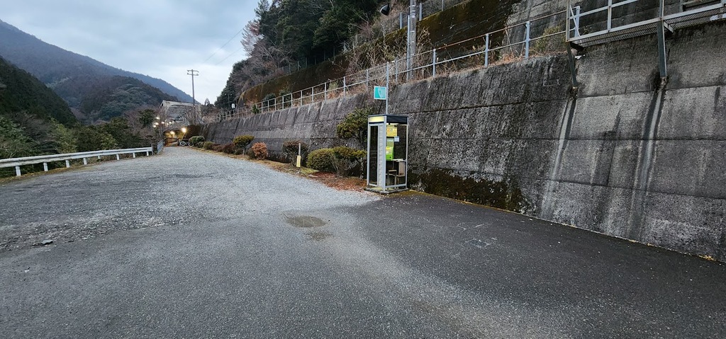駅前広場(?)にポツンと立つ黄色い街灯と緑の公衆電話